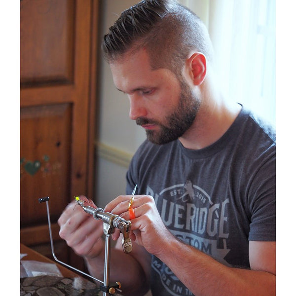 Man at a desk using scissors and fly tying materials