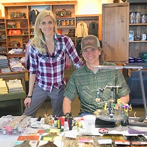 Man and woman working at a desk with fly tying materials