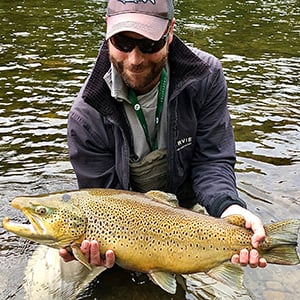 Man crouching over his yellow fish he caught