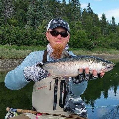 Man with sunglasses sitting in a boat while holding a caught fish