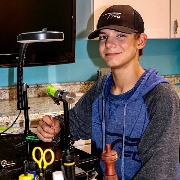 Boy at a desk working on crafting fly tying materials