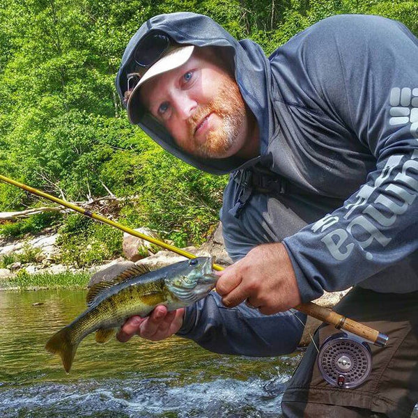 Fisherman with fishing pole and small fish near a stream